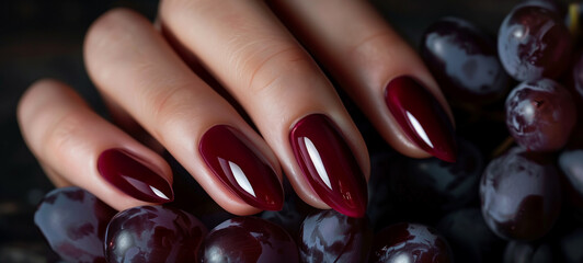 An elegant single-color manicure in deep burgundy, accompanied by the rich hues of ripe grapes