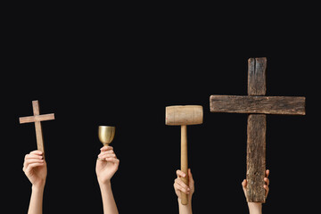 Female hands with wooden crosses, mallet and cup on dark background. Good Friday concept