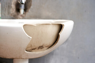 An old dirty broken ceramic sink in the cafeteria outside.