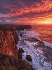 The setting sun bathes a rugged coastline in a breathtaking display of vibrant reds and oranges, as...