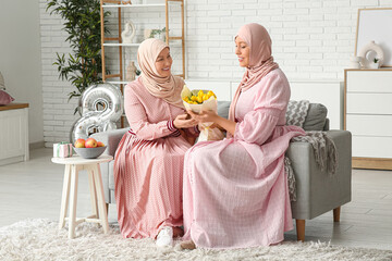 Muslim adult woman greeting her mother with bouquet of tulips at home. International Women's Day...
