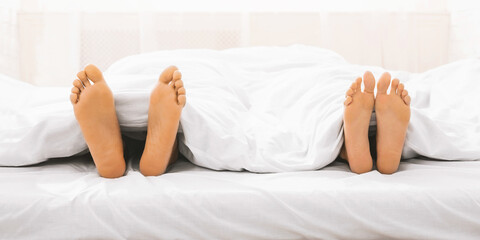Obraz na płótnie Canvas Feet of black couple in bed under blanket