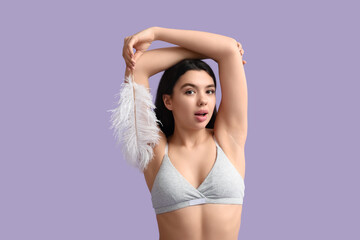 Obraz premium Beautiful young woman with soft feather on lilac background. Epilation concept