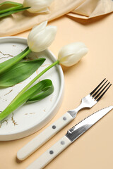 Beautiful table setting with white tulips on beige background