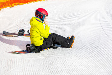 snowboarder sits on a snowboard on wet, loose snow before skiing. active recreation