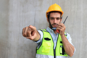 The gesture of a male engineer posing with a walkie-talkie. Strike a pose of a male engineer using a walkie-talkie.