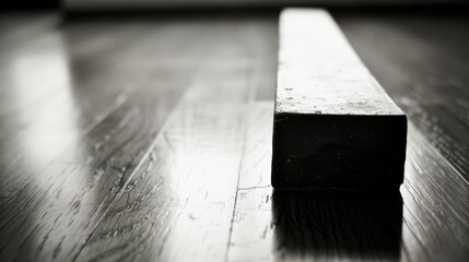   Black-and-white picture of wooden planks featuring a rectangular item positioned atop