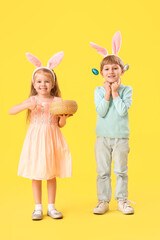 Little children in bunny ears with Easter eggs on yellow background