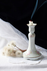 Still life with an antique porcelain candlestick and smoke from an extinguished candle,mood of loss...