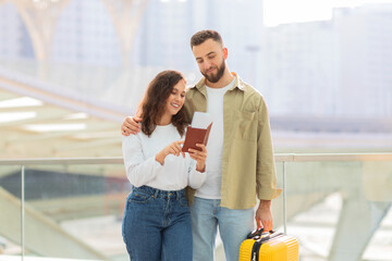 Couple looking at passport near glass railing