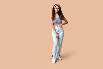 Fototapeta na wymiar Stylish African-American woman in top and jeans on beige background