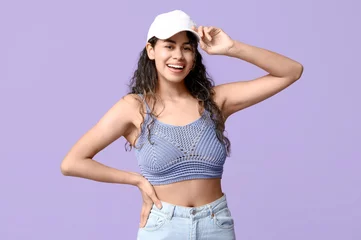 Foto op Canvas Stylish African-American woman wearing top, jeans and cap on lilac background © Pixel-Shot