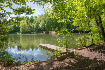 idyllic lake Thanninger Weiher, shore with boardwalk and trees with green leaves around