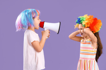 Little brother and sister with colorful wigs and megaphone on lilac background. April Fool's Day...