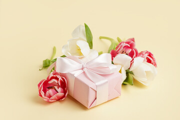 Gift box and beautiful tulips on yellow background