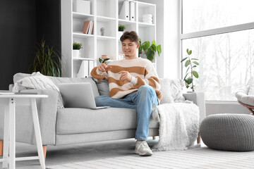 Male student studying online on sofa at home