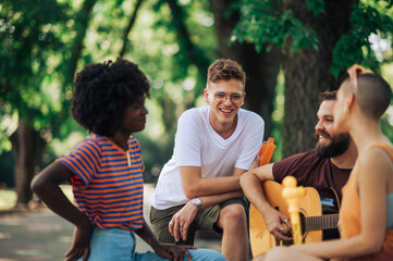 Four multiracial friends talking in the park during free afternoon.