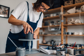 A talented pottery designer attaching wet clay at ceramics studio.