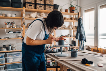 Precise craftswoman making handmade pottery and earthenware at studio.