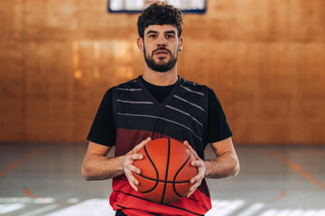 Naklejka premium A professional basketball player posing with a ball on basket court.
