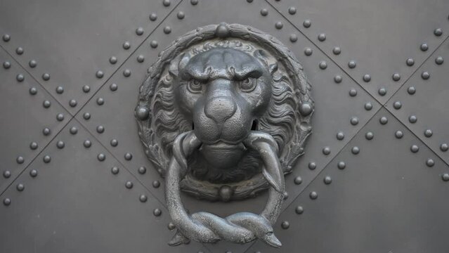 Close-up of a lion's head as a metal door knocker on a metal door - slow motion