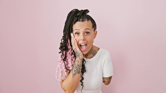Amputee hispanic woman in shock, panic-stricken, hands over amazed face, expressive tattooed armless beauty standing isolated over pink background