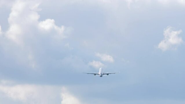 Aircraft in blue cloudy sky. Jet airplane taking off, departing, rear view. Silhouette of plane climbing to altitude.