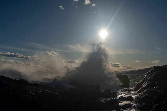 Waves crashing at cliff in sunlight. High quality photo