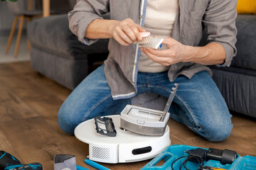a man repairs a robot vacuum cleaner, cleans the air filter of dust. an important procedure in the...