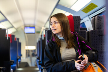 Caucasian woman traveler in jacket sitting inside train carriage.