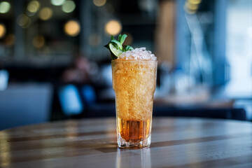 yellow cocktail with ice on a table in a cafe, blurred background