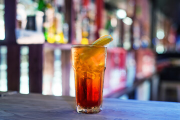 red cocktail with ice on a table in a cafe, blurred background