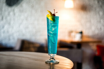 blue cocktail with ice on a table in a cafe, blurred background