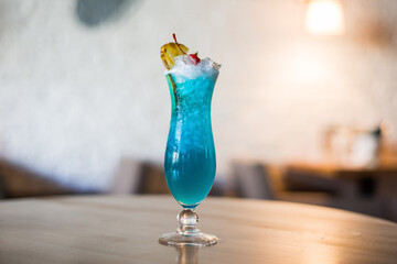 blue cocktail with ice on a table in a cafe, blurred background