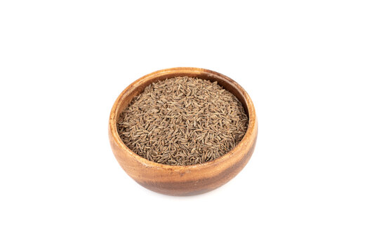 Aromatic cumin seeds in a wooden bowl on a white background.
