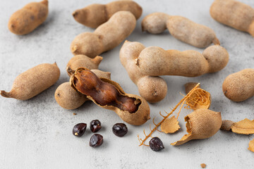 Ripe whole and shelled tamarind fruits  with seeds closeup on stone background.