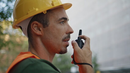 Building chief speaking wireless device at city closeup. Man using walkie-talkie