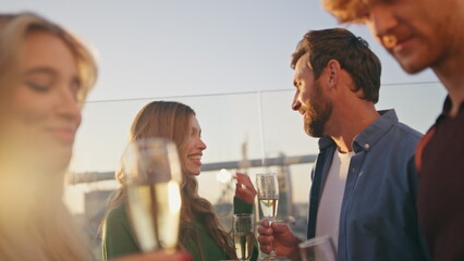 Smiling millennials drinking sparkling wine at rooftop party hangout close up. 