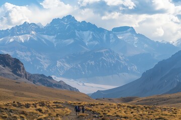 Excursionistas recorren un vasto y ondulante desierto, sus figuras empequeñecidas por la impresionante majestuosidad de picos imponentes, con el sol proyectando un dramático baile de luz y sombra.