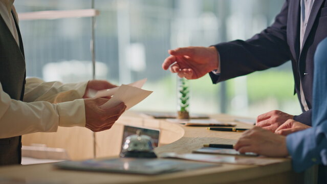 Receptionist hands giving keys at hotel counter closeup. Tourist couple check in