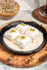 Baklava with white chocolate and milk. Cold baklava with chocolate on a wooden serving board. Famous dishes of Turkish cuisine