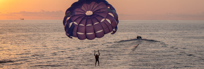 scene of a man parachuting with a purple parachute above the sea