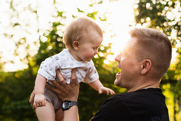 Dad holds his little daughter in his arms, summer sunset
