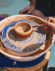 Fototapeta premium Pottery lesson master class for kids children, process of making clay pot on pottery wheel, potter hands creating ceramic crockery handcrafts, ceramist molding and painting jar or vase