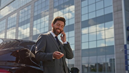 Satisfied businessman talking smartphone playing with car keys closeup zoom in.