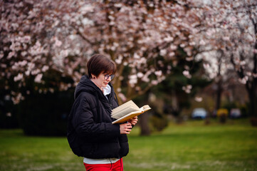 Absorbed in a good book, a woman enjoys a quiet moment of reading surrounded by the soft blooms of...