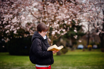 Absorbed in a good book, a woman enjoys a quiet moment of reading surrounded by the soft blooms of...