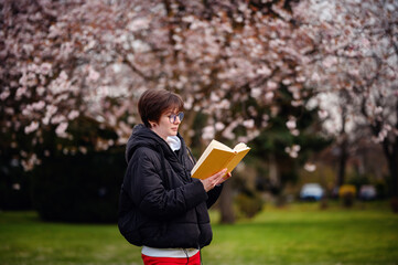 Absorbed in a good book, a woman enjoys a quiet moment of reading surrounded by the soft blooms of...