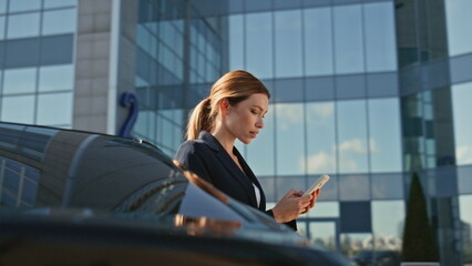 Corporate manager scrolling smartphone outside modern office building close up.