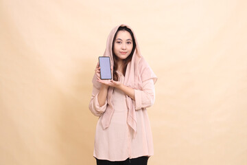 indonesia woman smiles at camera hand introducing cellphone gadget screen. young beautiful for business, technology, fashion